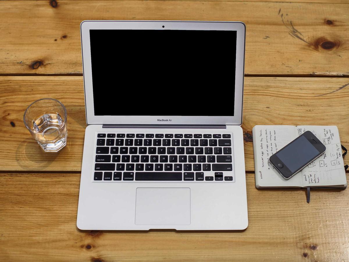 A clean desk with a laptop, glass of water and phone
