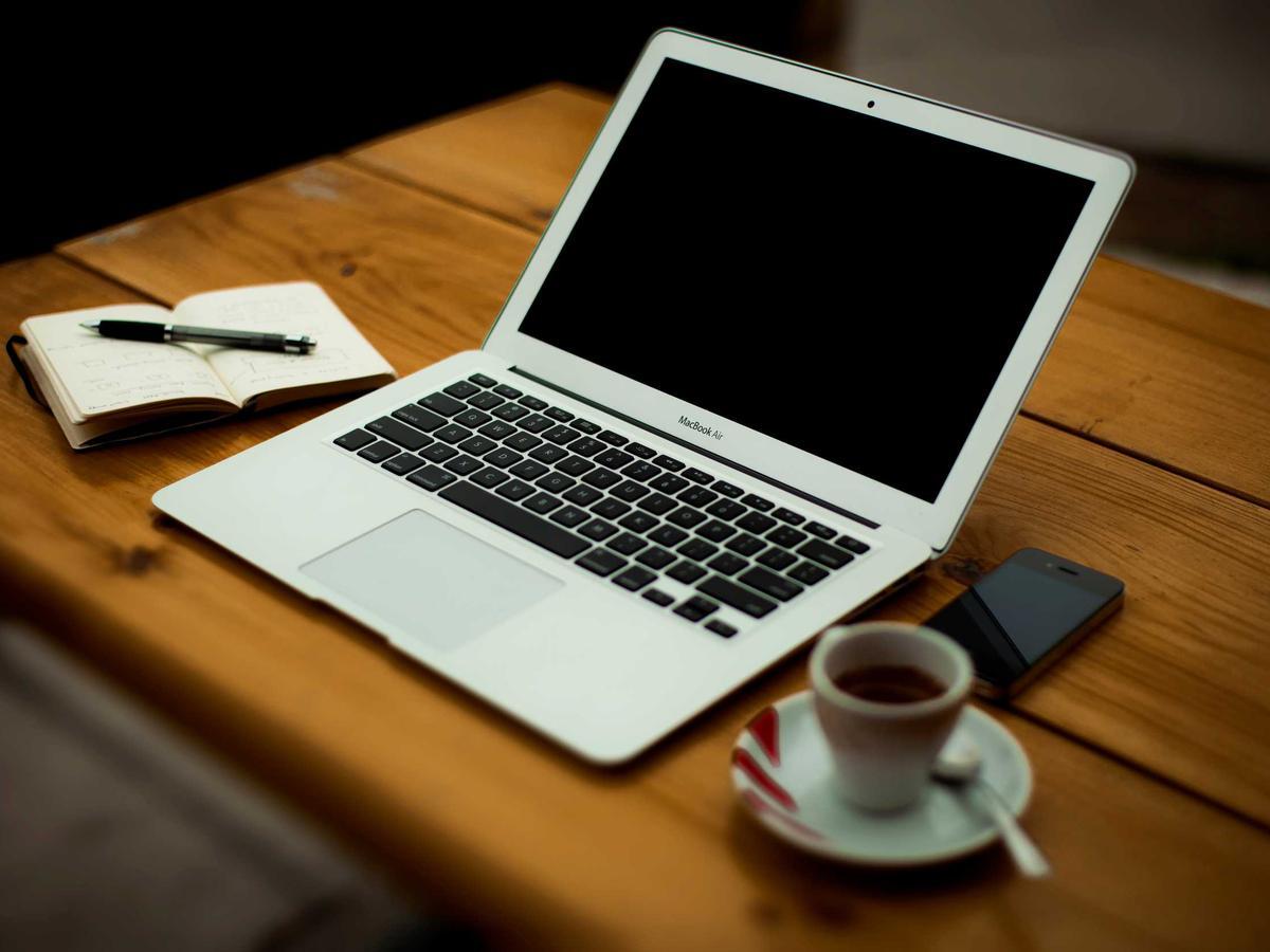 A laptop and open notebook with figures on a wooden desk